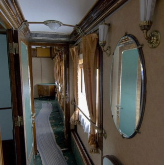 Railway Museum in Kyiv - narrow vintage train corridor lined with wood paneling, mirrors, and beige curtains evoking the atmosphere of past travel