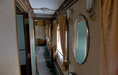 Railway Museum in Kyiv - narrow vintage train corridor lined with wood paneling, mirrors, and beige curtains evoking the atmosphere of past travel