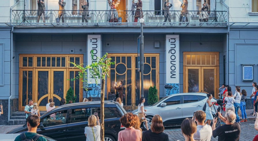 Molodyi Teatr in Kyiv - unique outdoor performance with actors in costumes acting on the theater's balcony while a crowd watches from the street below