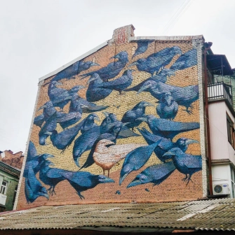 Messenger of Life in Kyiv - mural of white crow among flock, symbolizing that being unique is the norm