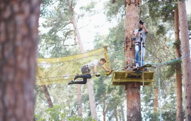 Seiklar Park in Kyiv - a man overcomes a yellow mesh tunnel obstacle suspended high above the ground