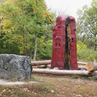 Lysa Hora in Kyiv - plarge red wooden idol with carved faces standing in a forest clearing