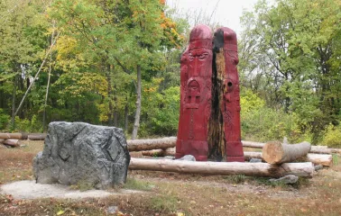 Lysa Hora in Kyiv - plarge red wooden idol with carved faces standing in a forest clearing