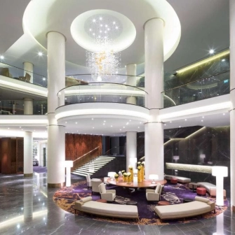 The luxurious lobby of the Hilton Kyiv Hotel with columns, a round seating area and a modern chandelier