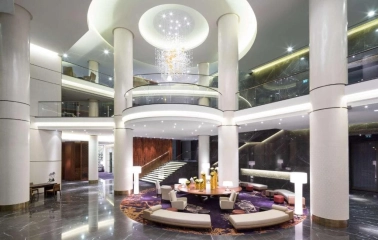 The luxurious lobby of the Hilton Kyiv Hotel with columns, a round seating area and a modern chandelier