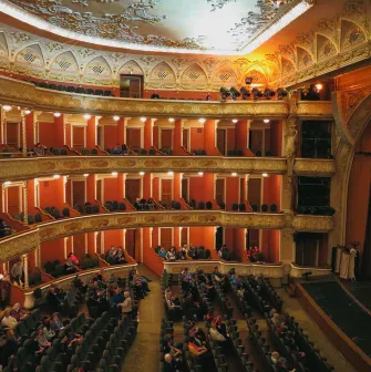 Teatr Franka in Kyiv - elegant interior of the historic theater featuring tiers of red balconies with ornate gold stucco details and seated audience