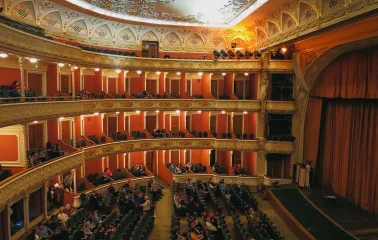Teatr Franka in Kyiv - elegant interior of the historic theater featuring tiers of red balconies with ornate gold stucco details and seated audience