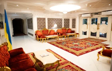 A grand, classic-style reception hall with red furniture at the Royal Olympic Hotel in Kyiv