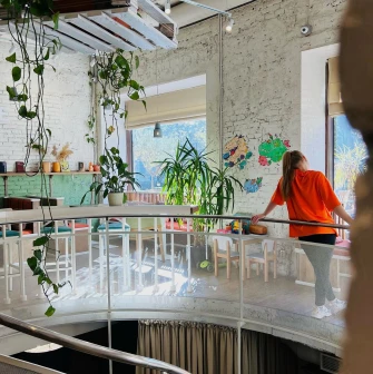 Restaurant Trishky Bilshe - upper floor balcony with plants and a girl leaning on the railing
