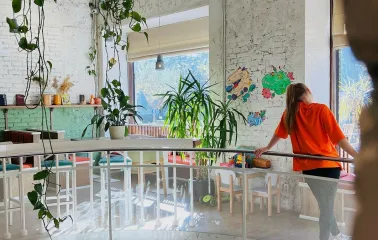 Restaurant Trishky Bilshe - upper floor balcony with plants and a girl leaning on the railing