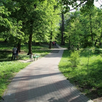 Park Kyn-Grust - shady alley with a paved path and stairs leading up a hill with people walking