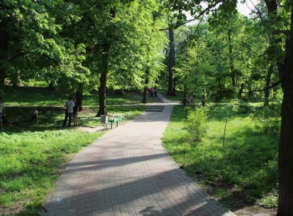 Park Kyn-Grust - shady alley with a paved path and stairs leading up a hill with people walking