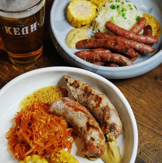 Pab Kedy - close-up of two plates with sausages cabbage and grilled corn