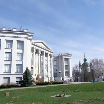 Volodymyrska Street in Kyiv - white classical museum building standing on the green hill near the church domes