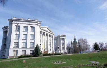 Volodymyrska Street in Kyiv - white classical museum building standing on the green hill near the church domes