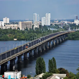 Aerial view of the Paton Bridge and the Dnieper River in Kyiv with the city skyline.