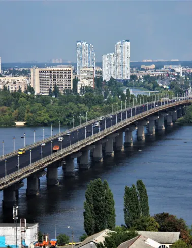 Aerial view of the Paton Bridge and the Dnieper River in Kyiv with the city skyline.