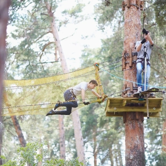 Seiklar Park in Kyiv - a man overcomes a yellow mesh tunnel obstacle suspended high above the ground
