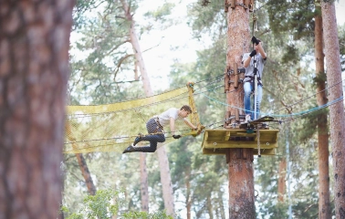 Seiklar Park in Kyiv - a man overcomes a yellow mesh tunnel obstacle suspended high above the ground
