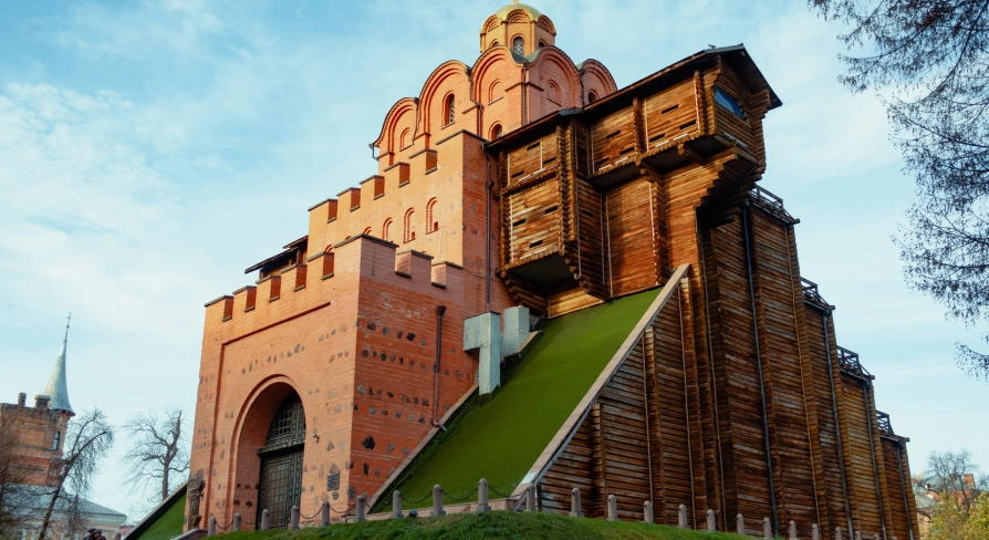 Golden Gate in Kyiv - reconstructed medieval gate with red brick walls, wooden fortifications and grassy slope