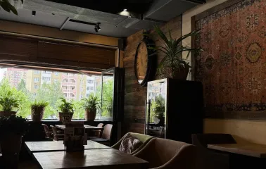 Chachapuri in Kyiv - dining corner with wall carpet, large clock and open window
