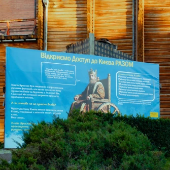 Golden Gate in Kyiv - informational poster near the wooden walls explaining the history and accessibility of the monument