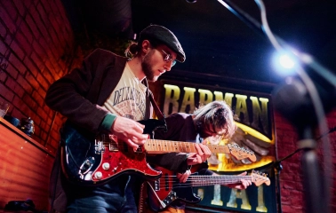 BarmanDictat - two musicians playing electric and bass guitars on a small stage