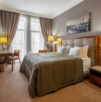 City Hotel in Kyiv - bedroom interior with double bed, painting and desk by the window