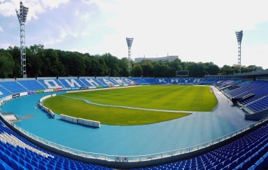 Dynamo Stadium in Kyiv - panoramic view from the stands showing the green pitch and blue seats with "Dynamo" and "Kyiv" lettering
