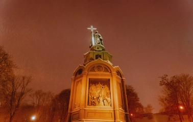 Monument to Vladimir the Great - illuminated statue holding a glowing cross on a snowy winter night