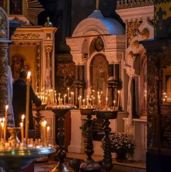St. Volodymyr's Cathedral in Kyiv - burning wax candles on brass stand in front of icons
