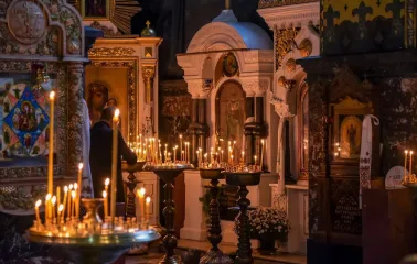 St. Volodymyr's Cathedral in Kyiv - burning wax candles on brass stand in front of icons