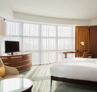 Deluxe room at Hilton Kyiv with a king-size bed, sofa and panoramic windows with yellow curtains