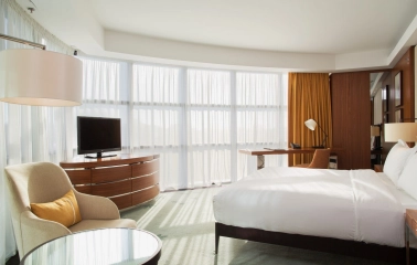 Deluxe room at Hilton Kyiv with a king-size bed, sofa and panoramic windows with yellow curtains
