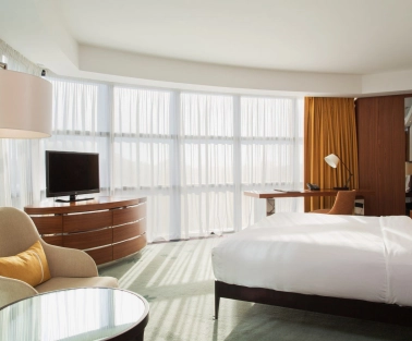 Deluxe room at Hilton Kyiv with a king-size bed, sofa and panoramic windows with yellow curtains
