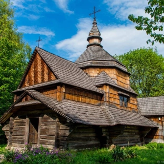 An eighteenth-century wooden church surrounded by greenery in the Pies Museum in Kyiv