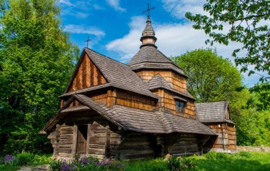 An eighteenth-century wooden church surrounded by greenery in the Pies Museum in Kyiv