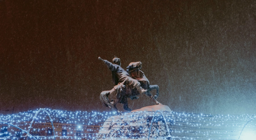 Monument to Bogdan Khmelnytsky in Kyiv - illuminated equestrian statue standing above festive Christmas lights on a snowy night