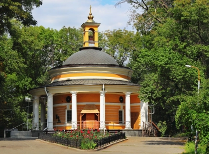 Askoldova Mohyla in Kyiv - iconic St. Nicholas Rotunda Church featuring bright yellow walls and white columns nestled among the peaceful park trees