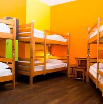 Bright dorm room with orange walls and wooden bunk beds at Dream Hostel in Kyiv