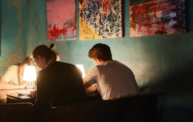 Visitors at a table during an evening at the restaurant with paintings on the walls