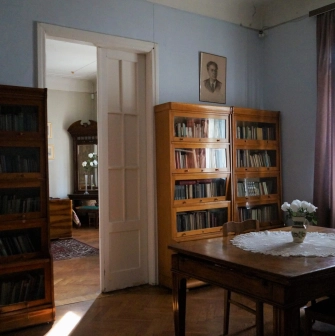 Muzei Tychyny in Kyiv - quiet study room with wooden bookcases, a table covered with a lace cloth, and a portrait of the poet on the wall