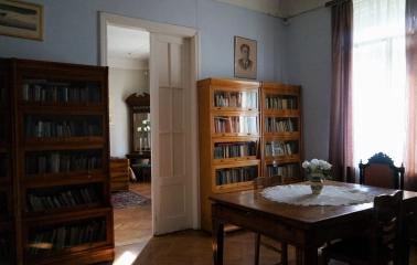 Muzei Tychyny in Kyiv - quiet study room with wooden bookcases, a table covered with a lace cloth, and a portrait of the poet on the wall