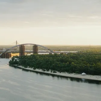 Dnipro river - view of the Podilsko-Voskresensky Bridge arch and sandy beach