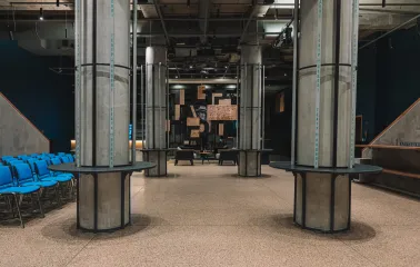 Teatr na Podoli in Kyiv - modern industrial foyer with concrete columns, blue chairs, and a logo wall
