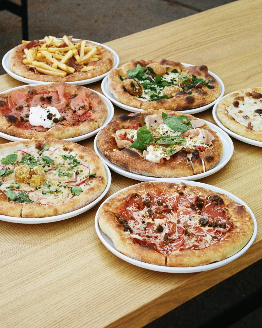 Various types of pizza on a wooden table at Autostation