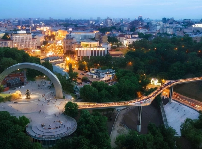Aerial night view of the illuminated Glass Bridge and Arch of Freedom in Kyiv