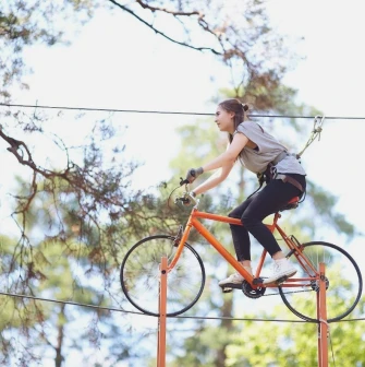 Seiklar Park in Kyiv - woman riding an orange bicycle suspended on a high wire
