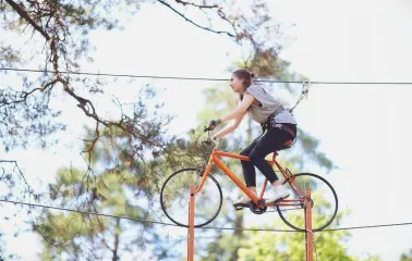 Seiklar Park in Kyiv - woman riding an orange bicycle suspended on a high wire