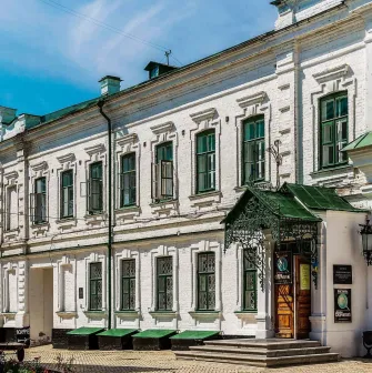 Mykola Syadristy Microminiatures Museum in Kyiv - historic white building with green framed windows and an ornate wrought-iron entrance canopy located in the Kyiv Pechersk Lavra